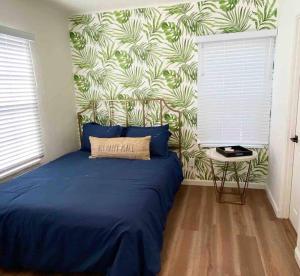 圣地亚哥Crown Point Home w/ Cowboy Pool 2 Blocks to Bay的一间卧室配有一张蓝色的床和热带壁纸