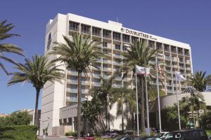 托伦斯托兰斯-南湾希尔顿逸林酒店的一座酒店大楼前面有棕榈树