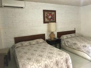 阿卡普尔科Hotel las hamacas的一间卧室设有两张床和砖墙