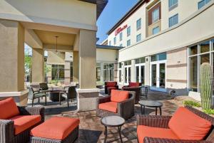 坦培亚利桑那州菲尼克斯/坦佩亚利桑那州立大学地区希尔顿花园酒店的酒店前方设有带桌椅的庭院。