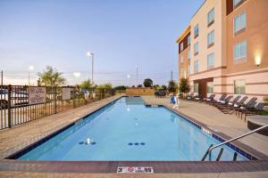 坦培亚利桑那州菲尼克斯/坦佩亚利桑那州立大学地区希尔顿花园酒店的一座带椅子的大型游泳池和一座建筑