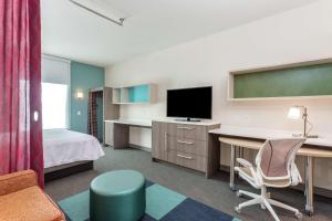 印第安纳波利斯Home 2 Suites By Hilton Indianapolis Northwest的酒店客房配有一张床和一张书桌及一台电视