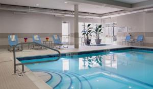 温尼伯温尼伯机场 - 马球公园希尔顿惠庭套房酒店的一个带蓝色桌椅的大型游泳池