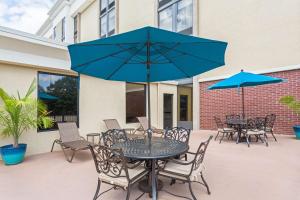 诺克罗斯Hampton Inn Norcross的一个带桌椅和蓝伞的庭院