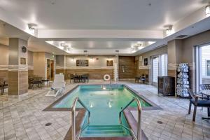 布鲁克林Homewood Suites by Hilton Boston Brookline-Longwood Medical的游泳池位于带桌椅的房间中间