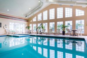 钦科蒂格Hampton Inn & Suites Chincoteague-Waterfront, Va的室内游泳池设有桌椅和窗户。