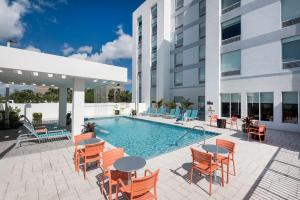 达尼亚滩Home2 Suites By Hilton Ft. Lauderdale Airport-Cruise Port的一座带桌椅的游泳池以及一座建筑