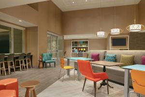 尚蒂伊Home2 Suites By Hilton Chantilly Dulles Airport的一间设有五颜六色的椅子和桌子的等候室