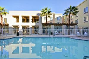 棕榈荒漠棕榈沙漠希尔顿惠庭套房酒店 的棕榈树建筑前的游泳池