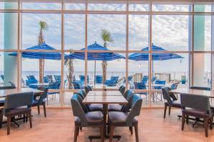巴拿马城海滩Hampton Inn & Suites Panama City Beach-Beachfront的一间带桌椅和蓝伞的餐厅