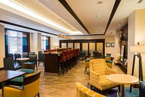渥太华渥太华机场希尔顿汉普顿酒店的一间带桌椅的餐厅和一间酒吧