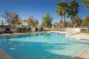 Suisun City萨斯城河岸汉普顿酒店及套房的一个带椅子和桌子的游泳池,并种植了棕榈树