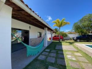 卡马萨里Casa Cantinho de Arembepe - Linda casa com piscina no litoral norte da Bahia的吊床挂在房子的一侧