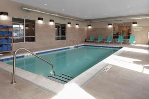 森特尼尔Home2 Suites By Hilton Denver South Centennial Airport的一个带蓝色椅子的酒店客房的游泳池