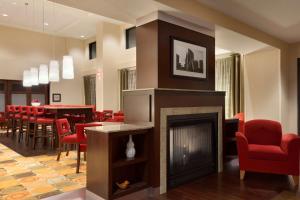 东哈特福德东哈特福德希尔顿恒庭旅馆&套房酒店的客房设有壁炉、红色椅子和桌子。