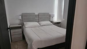 卡法亚特DEPARTAMENTOS CIELO DE CAFAYATE的一间卧室配有白色床和2个床头柜