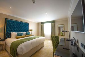 坎特伯雷贝斯特韦斯特阿博特巴顿酒店的一间卧室配有一张大床和蓝色床头板