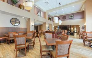 蒙克顿蒙克顿希尔顿恒庭套房酒店的餐厅设有木桌、椅子和时钟
