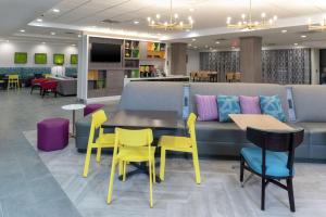 印第安纳波利斯Home2 Suites By Hilton Indianapolis Airport的一个带黄色桌椅和沙发的等候区