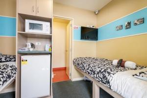 罗托鲁瓦Stay Hostel Rotorua的小房间设有两张床和微波炉