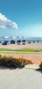 努沙杜瓦IKOSHAROLD Resort Benoa的海滩上摆放着桌椅和遮阳伞