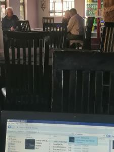 Okahatjipara Lodge的电脑屏幕,人们坐在餐厅的椅子上