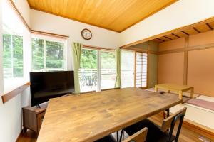 SengokuharaGreen Oasis Cottage Hakone Sengokuhara - グリーンオアシスコテージ箱根仙石原的一间带木桌和电视的用餐室