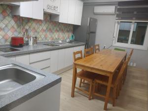 清州市T stay guesthouse的厨房配有木桌、椅子和水槽