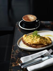 堪培拉A by Adina Canberra的餐桌,带两盘食物和一杯咖啡的桌子