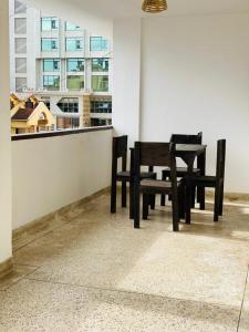 阿鲁沙Imbasa House - Arusha的两把木椅和一张桌子,位于窗户前