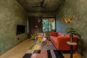 瓦加托Mossy - Aesthetic 2BHK Apartment - Vagator, Goa By StayMonkey的客厅配有红色的沙发和桌子