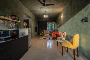 瓦加托Mossy - Aesthetic 2BHK Apartment - Vagator, Goa By StayMonkey的带黄色椅子的厨房和客厅