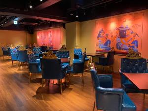 东京Sauna & Cabin Thermae-yu Nishiazabu的一间配备有蓝色椅子、桌子和绘画的用餐室