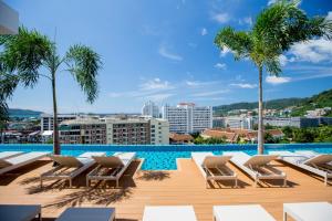 芭东海滩The Marina Phuket Hotel的一个带躺椅的游泳池,棕榈树