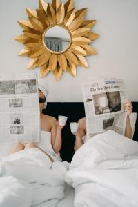 费尔兹姆斯Hubertus Boutiquehotel Filzmoos的坐在床上看报纸和喝咖啡的女人
