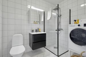 卑尔根Lys & luksuriøs leilighet midt i Bergen sentrum!的白色的浴室设有水槽和洗衣机。