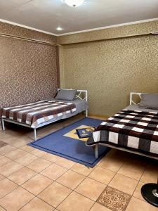 奇姆肯特InJoy Hostel的一间带两张床的卧室和地毯