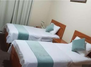 沙迦Al Jazeerah Hotel的配有两张床铺的酒店客房,配有绿色和白色床单