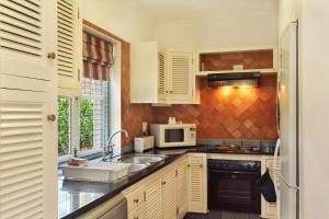 爱德华港Caribbean Estates Holiday Resort的厨房配有白色橱柜、水槽和微波炉