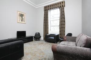 爱丁堡Cairn Hotel & Apartments的带沙发、电视和窗户的客厅