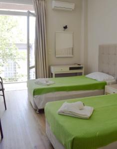 卡拉马塔City Center Hotel的客房设有两张带绿床单的床和窗户。