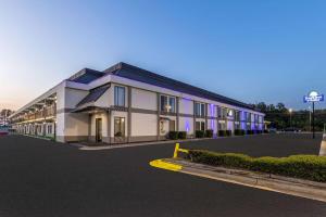 费耶特维尔Days Inn & Suites by Wyndham Fort Bragg/Cross Creek Mall的停车场内紫色照明的大型建筑
