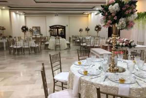 巴兰基亚巴兰基亚凡尔赛豪生国际酒店的宴会厅配有白色的桌椅和鲜花