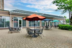 路易斯威尔路易斯维尔机场希尔顿花园酒店的一个带桌椅和遮阳伞的庭院