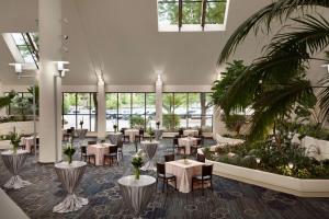 圣路易斯帕克明尼阿波利斯公园双树酒店的一间设有桌椅的餐厅,种植了棕榈树