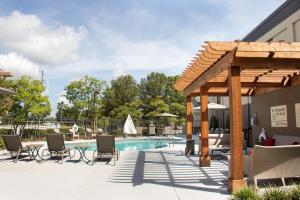 塔斯卡卢萨塔斯卡卢萨大学汉普顿酒店的一个带椅子的游泳池以及一个木制凉亭