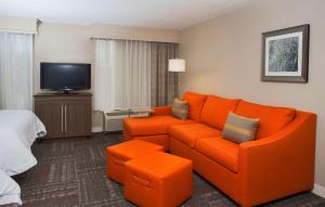 瓦尔多斯塔瓦尔多斯塔/会议中心汉普顿旅馆及套房酒店的客厅配有橙色沙发和电视