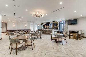 达拉斯Hilton Garden Inn Dallas-Central Expy/North Park Area, Tx的一间带桌椅的餐厅和一间酒吧