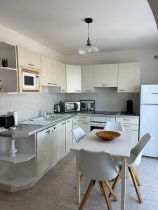 利勒鲁斯Appartement rez de villa的厨房配有白色橱柜和桌椅