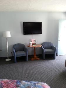 富兰克林卡罗来纳汽车旅馆的一间设有两把椅子、一台电视和一张桌子的房间